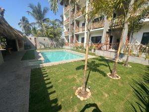 a swimming pool in front of a building with palm trees at Hotel Almendros Bonfil in Acapulco