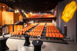 an empty auditorium with orange seats in a theatre at Hotel Base Camp Lodge - Albertville in Albertville +176 photos