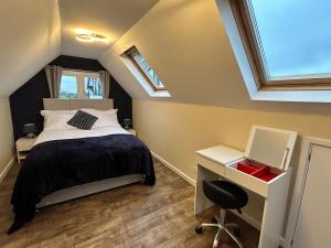 a bedroom with a bed and a desk and windows at The old greengrocers Battlesbridge in Rawreth