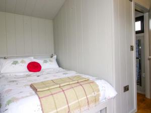 a bedroom with a bed with a red pillow on it at Leafy Oaks Cabin in Much Wenlock