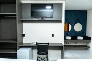 a room with a desk with a chair and a tv at Hotel Rota 090 in Piraí do Sul