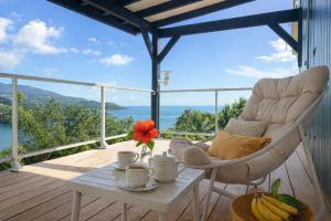 a chair and a table on a deck with a view at Villa 4 étoiles Le Pic de Malendure in Bouillante