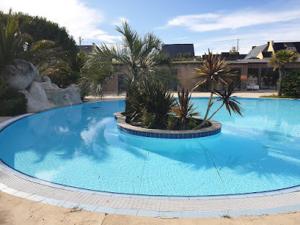 a large blue swimming pool with palm trees in it at Mobilhome Océalia T3 in Plouescat
