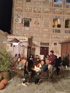 a group of people sitting around a fire in front of a building at Hotel Shekhawati Mandawa in Mandāwa