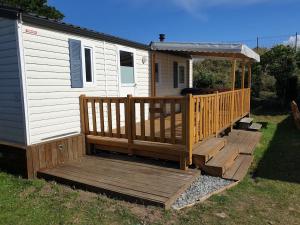 a mobile home with a wooden porch and a deck at Mobilhome Océalia T3 in Plouescat
