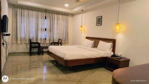 a bedroom with a bed and a table and a window at Hotel Raya's Annexe 1 in Kumbakonam