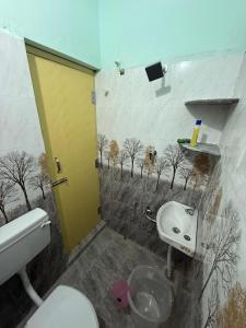 a bathroom with a toilet and a sink with trees on the wall at JMS Garden Villa in Kanchipuram