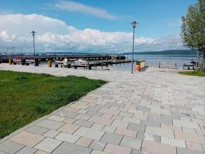 a pier with two people sitting on benches near the water at Ferienwohnung Dietz in Dießen am Ammersee +6 photos