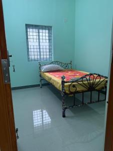 a small bed in a room with a blue wall at JMS Garden Villa in Kanchipuram
