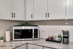 a kitchen with white cabinets and a silver microwave at Upscale Midtown Studio and Private Balcony in Raleigh