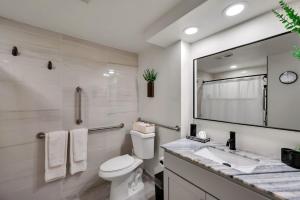 a bathroom with a toilet and a sink and a mirror at Upscale Midtown Studio and Private Balcony in Raleigh