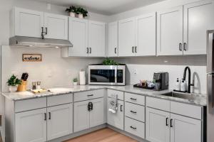 a white kitchen with white cabinets and a microwave at Upscale Midtown Studio and Private Balcony in Raleigh
