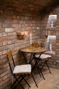 a table with two chairs and a candle on a brick wall at Volt Egyszer Egy Apartman Pécs in Pécs +9 photos