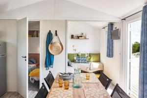 a dining room with a table and a living room at Camping La Siesta - Maeva in L'Aiguillon-la-Presqu'île