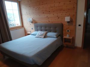 a bedroom with a large bed with a wooden wall at Casa Micéi in Tesero