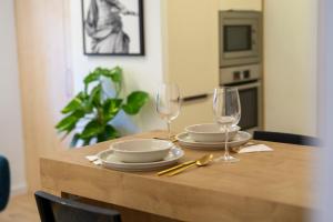 a wooden table with two plates and glasses on it at Volt Egyszer Egy Apartman Pécs in Pécs