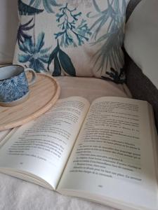 an open book on a bed with a cup of coffee at Gîte " Ô PARADIS" in Douelle
