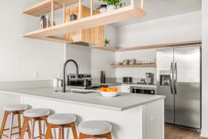 a kitchen with a counter with stools and a refrigerator at The Eighteen by Kasa in Nashville