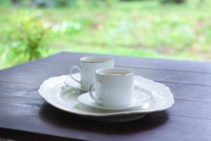 two white coffee cups sitting on a wooden table at Victoria Nature Resort in Digana +30 photos