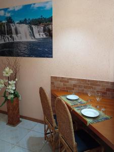 a table with chairs and a picture of a waterfall at Pousada Flor De Lótus Cipó in Serra do Cipo