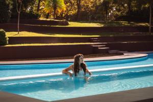 a woman is sitting in a swimming pool at Onyria Marinha Cascais, Vignette Collection by IHG in Cascais