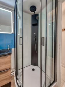 a shower in a caravan with glass doors at Le Duplex Cosy in Clermont