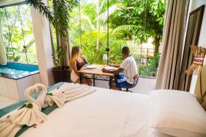 two people sitting at a table in a hotel room at Villa Botanic Garden in Itacaré