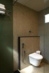 a bathroom with a toilet and a glass shower stall at illa - By the sea in Udupi