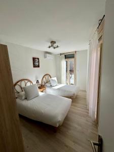 a room with two beds and a window at Logis Hotel-restaurant Les Glycines in Arles-sur-Tech