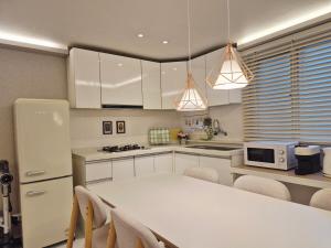 a kitchen with a white table and a white refrigerator at Maison Stay in Samgong