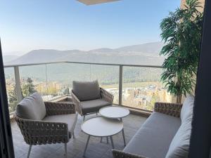 a balcony with chairs and a table and a view at יוקרה במצפה צפת in Safed