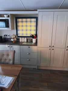 a kitchen with white cabinets and a wooden table at St Minver Hideaway in Saint Minver +2 photos
