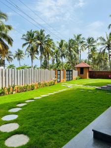 a grassy yard with a walkway and palm trees at illa - By the sea in Udupi