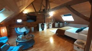 a bedroom with a bed and chairs in a attic at Chambre d'hôte de la Source Bleue in Cusance