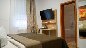 a bedroom with a bed and a bathroom with a television at Hotel Maximilian in Zeitz