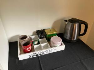 a tray with cups and a tea kettle on a table at Grande chambre indépendante in Bruz