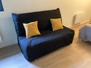 a black couch with two yellow pillows on it at Grande chambre indépendante in Bruz
