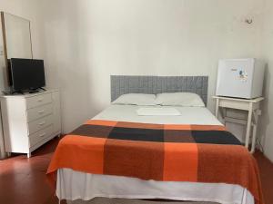 a bedroom with a bed and a dresser with a tv at Pousada Cisne Branco in Natal