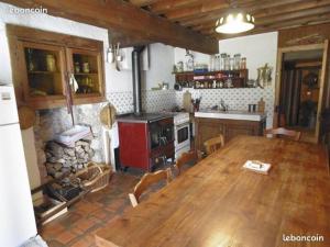 a kitchen with a wooden table and a fireplace at La Sauvagine in Les Fourgs