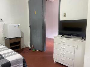 a bedroom with a tv and a dresser with a bed at Pousada Cisne Branco in Natal
