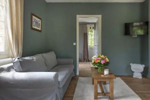 a living room with a couch and a table with flowers at La Petite Affolante in Samois-sur-Seine