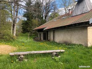 an old building with a bench in the grass at La Sauvagine in Les Fourgs