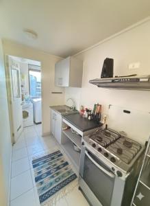 a white kitchen with a stove and a sink at Jacinta in Puerto Montt +1 photo