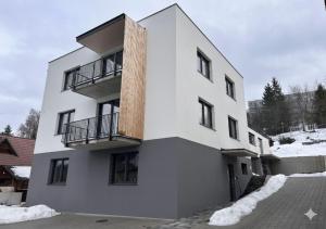 a white building with a balcony on the side of it at Apartmánový dom DK Ateliér in Dolný Kubín