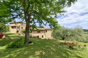 a stone house in a field with a tree at Villa Montepulciano by Mmega in Montepulciano