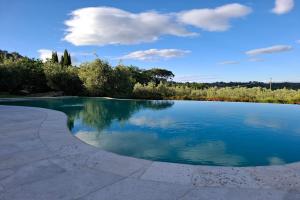 a pool of water with trees and clouds in the background at Villa Montepulciano by Mmega in Montepulciano