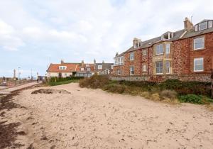 a house on the beach next to a building at Sandy Neuk in North Berwick