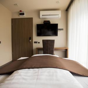 a bedroom with a bed and a tv on the wall at Pole Position Beach Hotel in Balatonszárszó