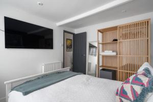 a bedroom with a bed and a flat screen tv at Modern Cottage in Central Exeter in Dean