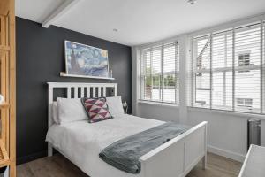 a bedroom with a white bed and two windows at Modern Cottage in Central Exeter in Dean